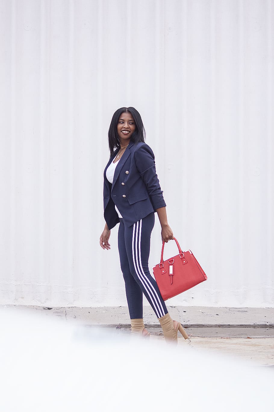 Navy blazer over white tank, navy stretch pants with white stripes down side, red handbag and sexy shoes