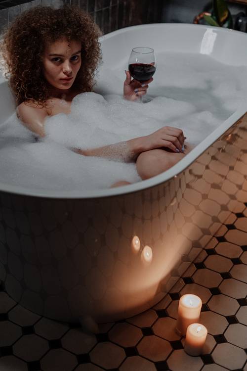 woman in bathtub with bubble bath and candles burning