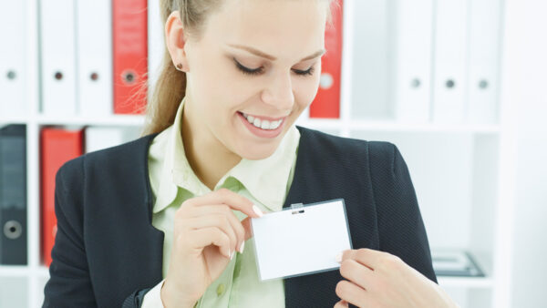 Happy smiling young business woman wearing blank badge. Name tag on chest. Person identity label. Business card mockup.