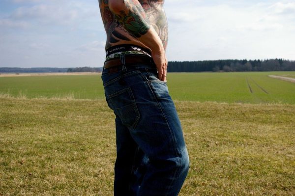 man with upper body tattoos in blue jeans