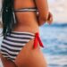 brunette woman in blue and white striped bikini with red tie